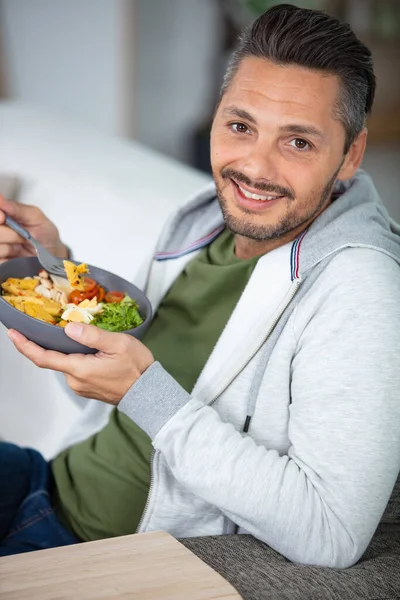 young man eating vegetarian salad with appetite