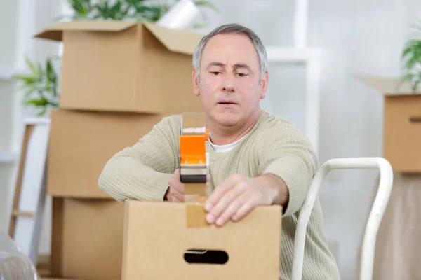 mature man using duct tape for packing stuff in box