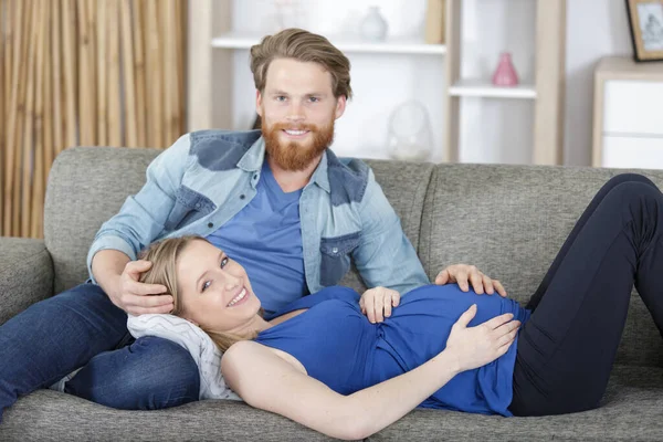 孕妇躺在伴侣的腿上躺在沙发上 — 图库照片