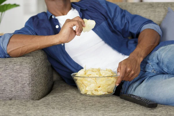 テレビを見ながらお菓子を食べる男の姿が切り取られ — ストック写真