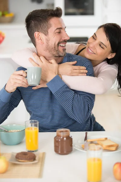 在厨房吃早餐的时候 年轻漂亮的一对幸福的情侣拥抱在一起 — 图库照片