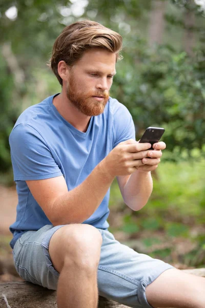 Atractivo Joven Sentado Parque Usando Teléfono Móvil —  Fotos de Stock