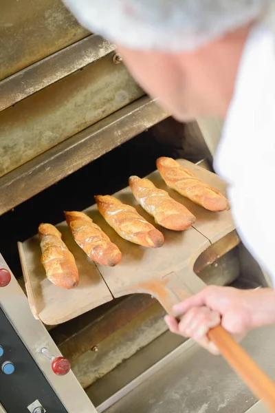 Bakker Neemt Vijf Stokbrood Schil Uit Broodoven — Stockfoto