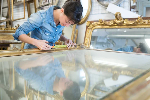 woman measuring a large antique mirror