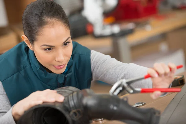 女性の整備士が車の部品をペンチで組み立てる — ストック写真