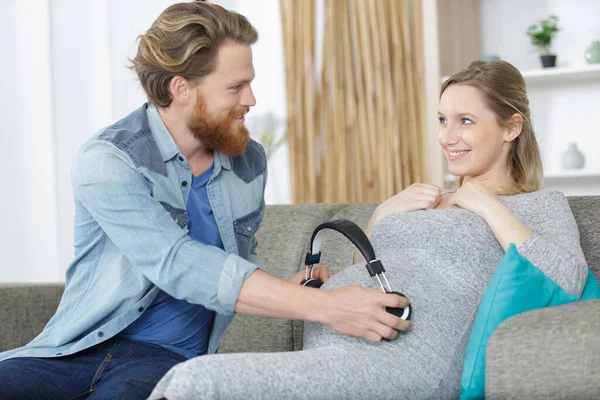 Husband Putting Wireless Headphones Wifes Belly — Stock Photo, Image