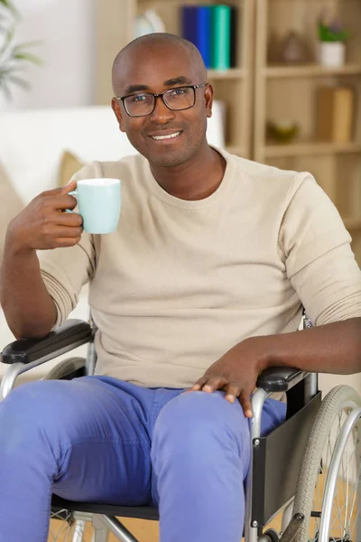 happy man inn a wheelchair drinking a cup of coffee