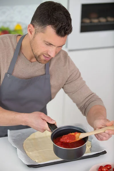 Mann Löffelt Tomatensauce Auf Pizzaboden — Stockfoto