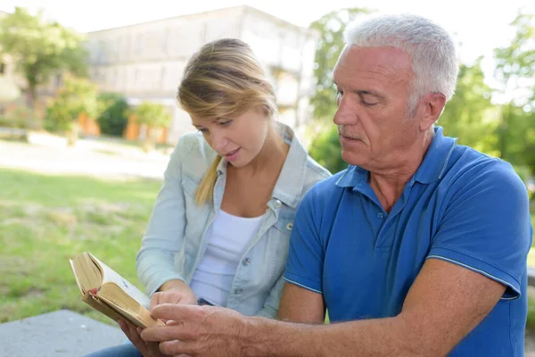 Kvinna Tittar Bok Med Sin Far — Stockfoto