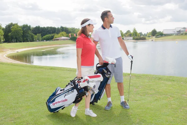 Pareja Jugadores Golf Con Palos Caminando Green —  Fotos de Stock