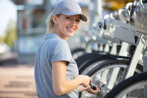 Kiralık Şehir Bisikletlerine Hizmet Veren Genç Bir Kadın — Stok fotoğraf