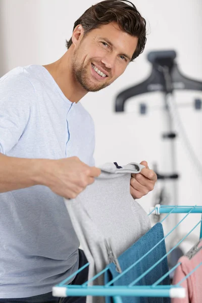 Mann Breitet Wäsche Haus Auf Einem Kleiderpferd Aus — Stockfoto