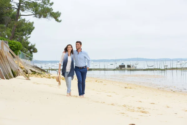 夫婦は手を取りながらゆっくりと海岸を歩き — ストック写真