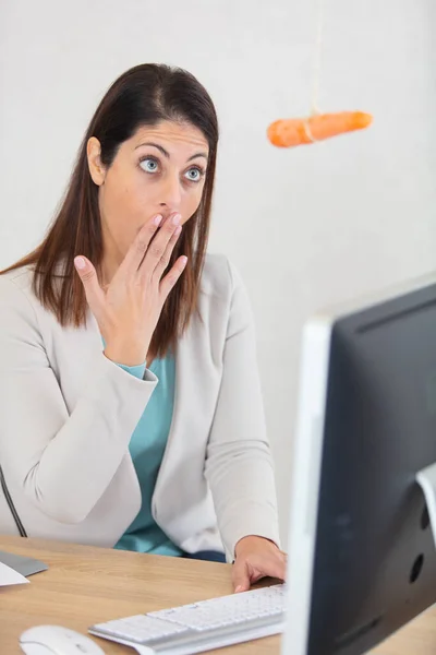 Mujer Escritorio Oficina Mira Con Sorpresa Zanahoria Colgando —  Fotos de Stock