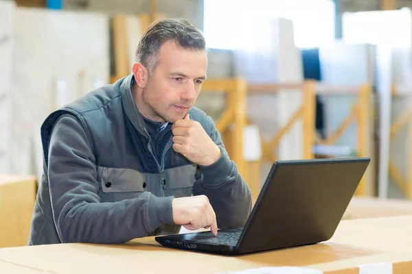 Mężczyzna Pracownik Patrząc Laptopa Warsztacie — Zdjęcie stockowe