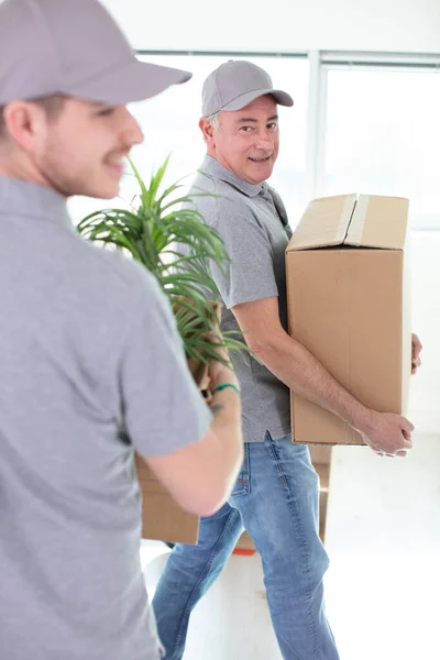 two cheerful removals men carrying belongings