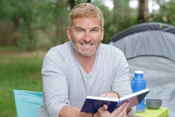Senior Man Leest Naast Zijn Tent — Stockfoto