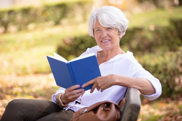 Donna Pensione Che Legge Libro Sulla Panchina Del Parco — Foto Stock