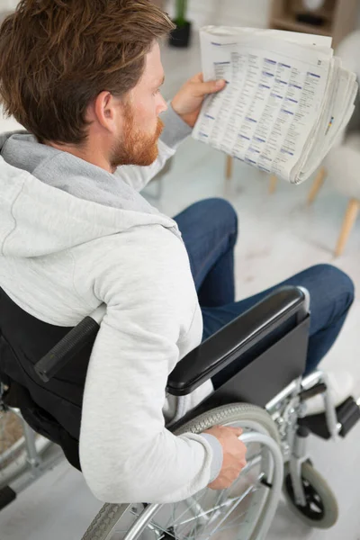 車椅子に座って新聞を読んでいる男 — ストック写真