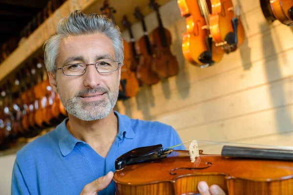 mature violin maker while testing the violins in his laboratory