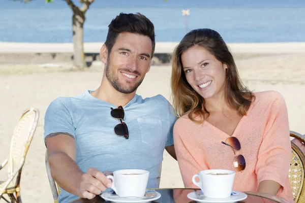 坐在餐厅里欣赏大海的情侣们喝咖啡 — 图库照片