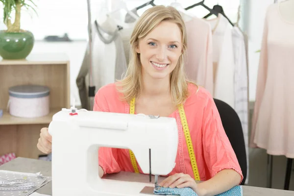 beautiful smiling tailor enjoying work on sewing machine