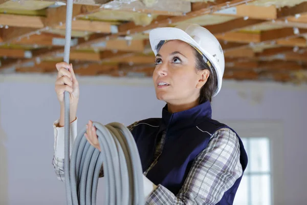 天井に換気を設置する女性電気技師は — ストック写真