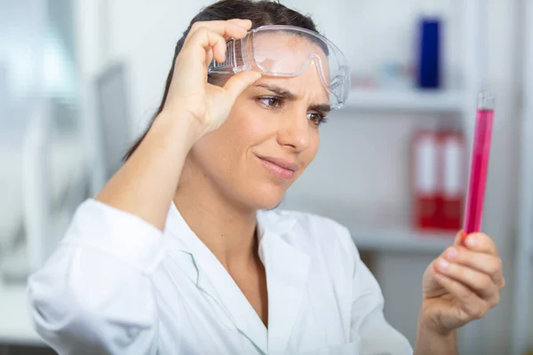 Vrouwelijke Wetenschapper Tillen Bril Inspecteren Reageerbuis — Stockfoto