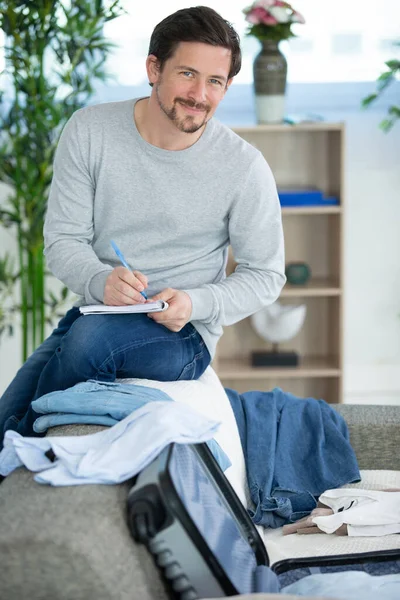 Homem Fazendo Lista Enquanto Mala Embalagem — Fotografia de Stock