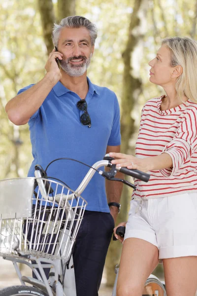 Gelukkige Volwassen Paar Met Fiets Zoek Mobiele Telefoon — Stockfoto