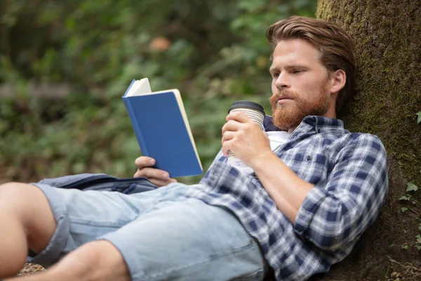 Młody Zrelaksowany Człowiek Czytając Książkę Przyrodzie — Zdjęcie stockowe