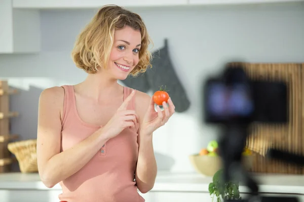 woman filming food blog is holding a tomato