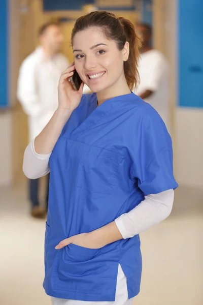 Enfermeira Usando Telefone Celular Com Médicos Discutindo Segundo Plano — Fotografia de Stock