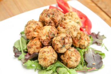 Yeşil salatayla servis edilen köfteler.