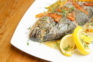 Domates soslu ızgara balık ve limon dilimleri.