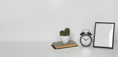 Masada siyah alarmlı ahşap çerçeve modeli. Nötr renk paletindeki iç dekorasyon elementleri. Beyaz duvar arkaplanı. 