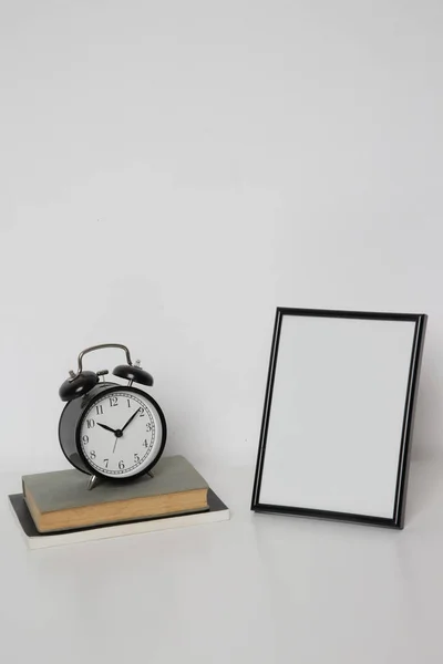 黒い目覚まし時計付きのテーブルの上に木製のフレームモックアップ ニュートラルカラーパレットのホームインテリア装飾要素 白い壁の背景 — ストック写真