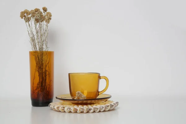 テーブルの上にドライフラワーとティーカップ付きの黄色のガラス花瓶 コピースペース付きのシンプルな家庭の装飾 — ストック写真