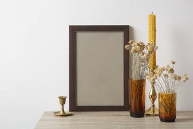 Masada ahşap çerçeve modeli ve iç dekorasyon unsurları var. Beyaz duvar arka planı. Nötr renk paleti.