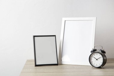 Masada siyah alarmlı ahşap çerçeve modeli. Nötr renk paletindeki iç dekorasyon elementleri. Beyaz duvar arkaplanı. 