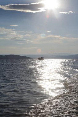 Öğleden sonra ufukta balıkçı teknesi olan deniz manzaralı bir yer.