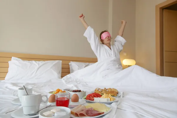 美しい若い女性が朝起きてベッドでストレッチ ベッドの上の朝食トレイ 忙しい日の前に穏やかな牧歌的な朝 — ストック写真