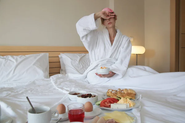 Νεαρή Νυσταγμένη Γυναίκα Ροζ Μάσκα Ύπνου Τρώει Πρωινό Στο Κρεβάτι — Φωτογραφία Αρχείου