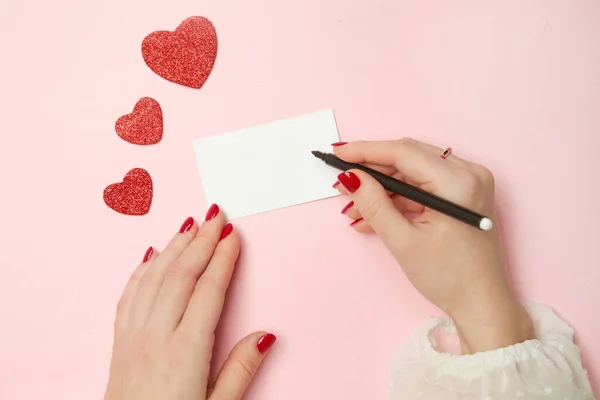 手とペンでグリーティングカード キラキラしたハートのピンクの背景に空白の白いカード テキストのための空のスペースでモックアップ 休日の背景 バレンタインデー 女性や母の日 — ストック写真