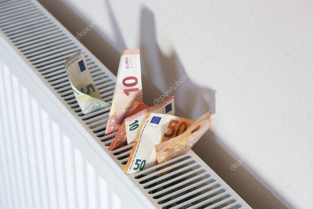 Home heating expenses and savings concept. Money on heating radiator.