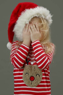 Noel Baba şapkalı üzgün kız elleriyle yüzünü kapatıyor. Kış tatilleri stres konsepti.