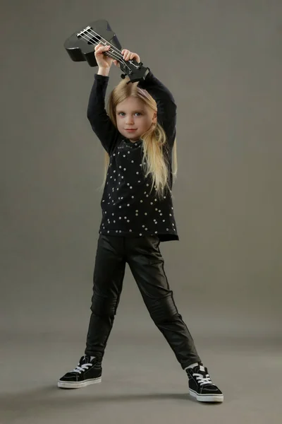 スタジオポートレートの幼児の女の子ギタリスト速報彼女のギター スタジオショップの灰色の背景 — ストック写真