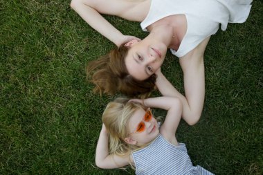 Anne ve kızı çimlerin üzerinde yatıyor, yaz boyunca doğada vakit geçiriyorlar.