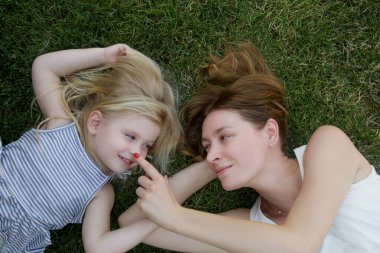 Anne ve kızı çimlerin üzerinde yatıyor, yaz boyunca doğada vakit geçiriyorlar.