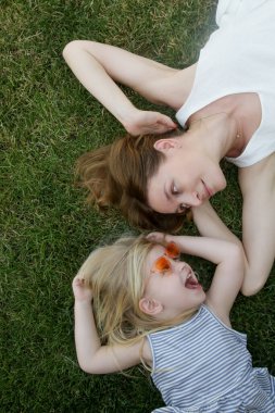 Anne ve kızı çimlerin üzerinde yatıyor, yaz boyunca doğada vakit geçiriyorlar.